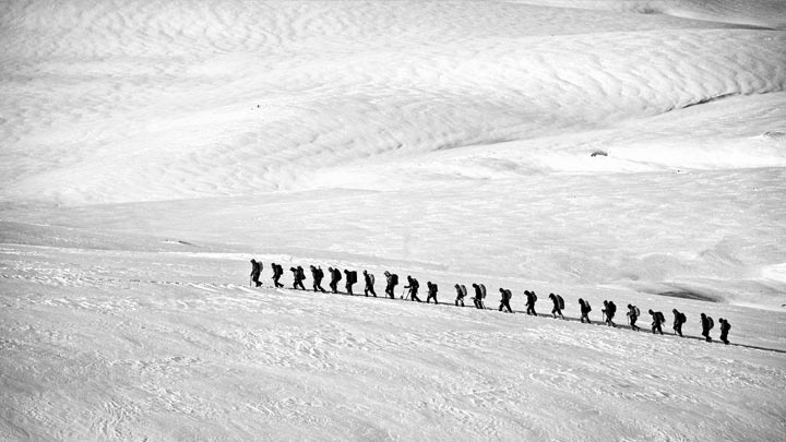 Groupe de personnes en cordée dans un paysage de montagnes enneigées
