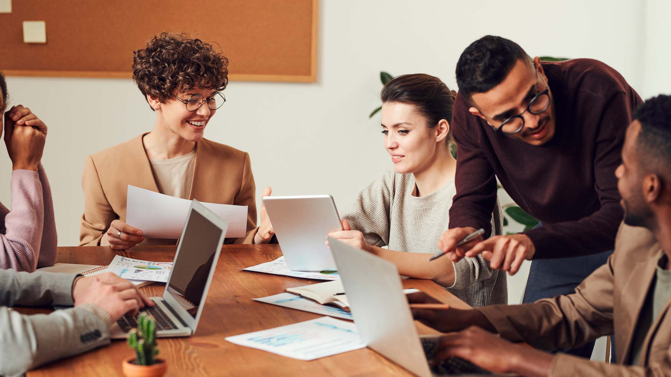 Groupe de 6 collaborateurs au travail autour d'un bureau en entreprise